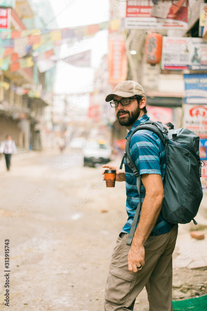 Happy man looking back with cup in hand walking through street Happy man looking back with cup in hand walking through street