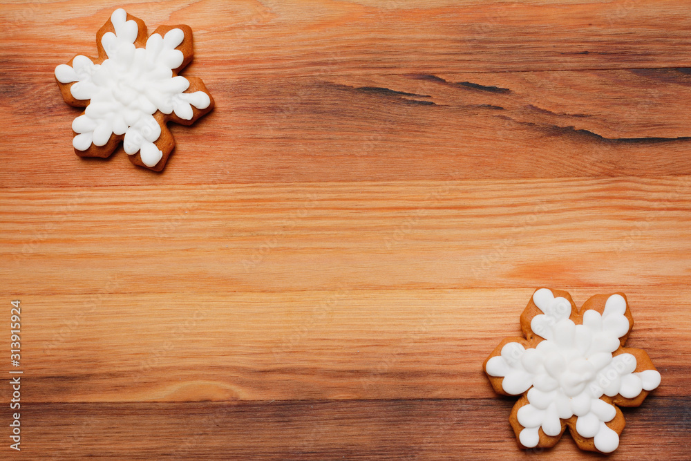 Two festive gingerbread in the shape of snowflakes on a wooden background copy space