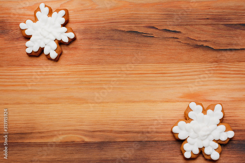 Two festive gingerbread in the shape of snowflakes on a wooden background copy space