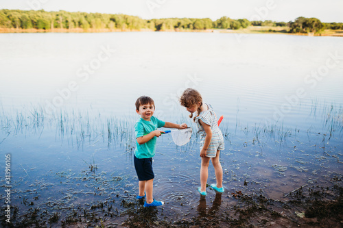 Young boy showing girl a fish he caughte in water at the lake