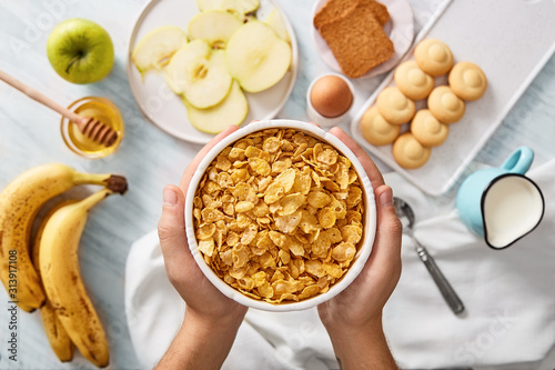 Man holding bowl of cereals. Rich breakfast ingredients. Top view photo