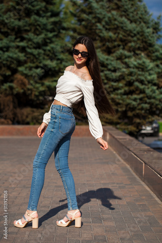 Pretty stylish brunette girl in blue jeans and white blouse