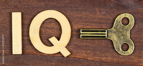 Web banner of intelligence quotient, iq test, brain concept, winding key with letters on a brown wooden background