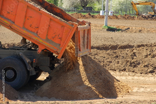Konstfotografi Big tipper truck unload sand on construction site on Sunny summer day