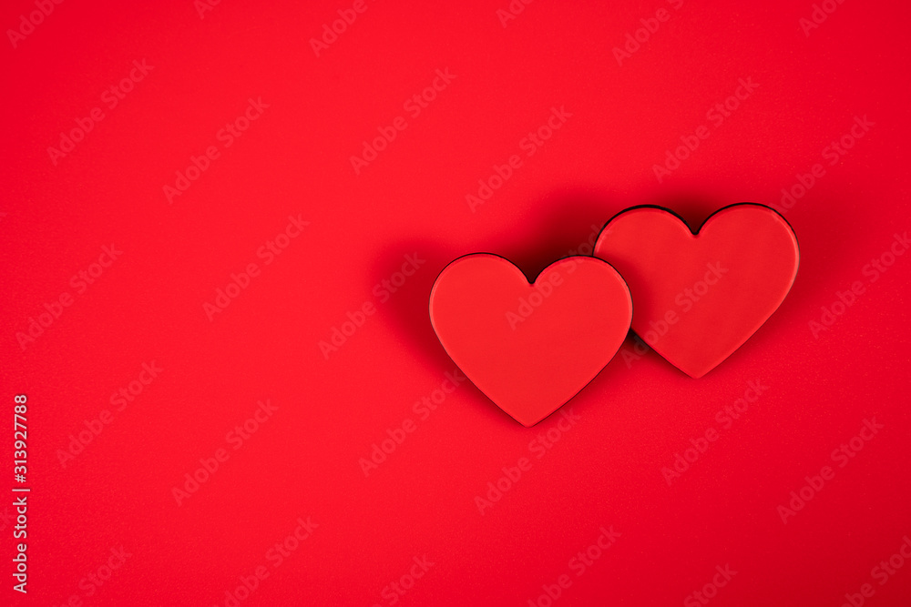 Two red hearts representing the love of two on a red background for Valentine's Day, wedding and other holidays, view from the top.
