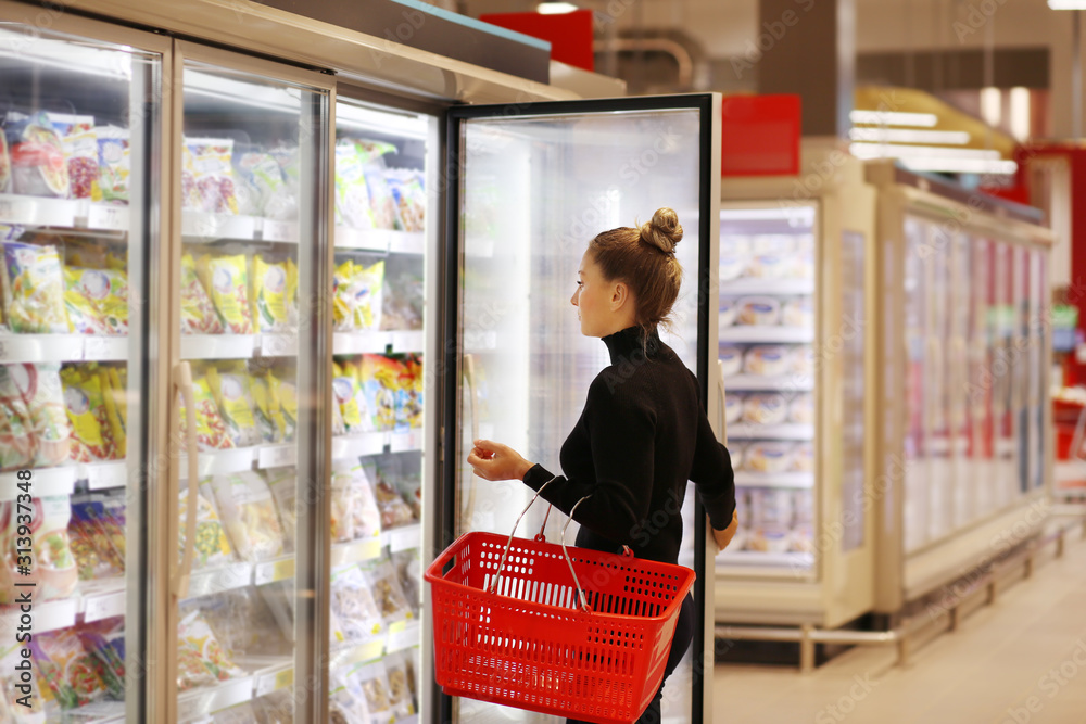 Woman choosing frozen food from a supermarket freezer