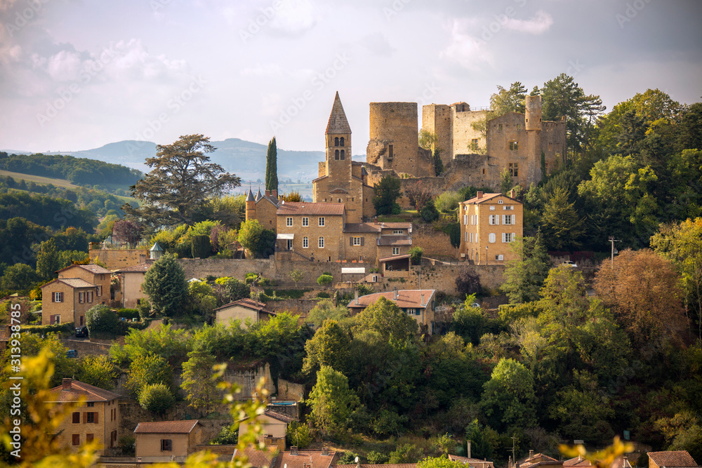 A fairytale village, complete with stone castle and stone church sits on a hill overlooking a valley in wine country France.