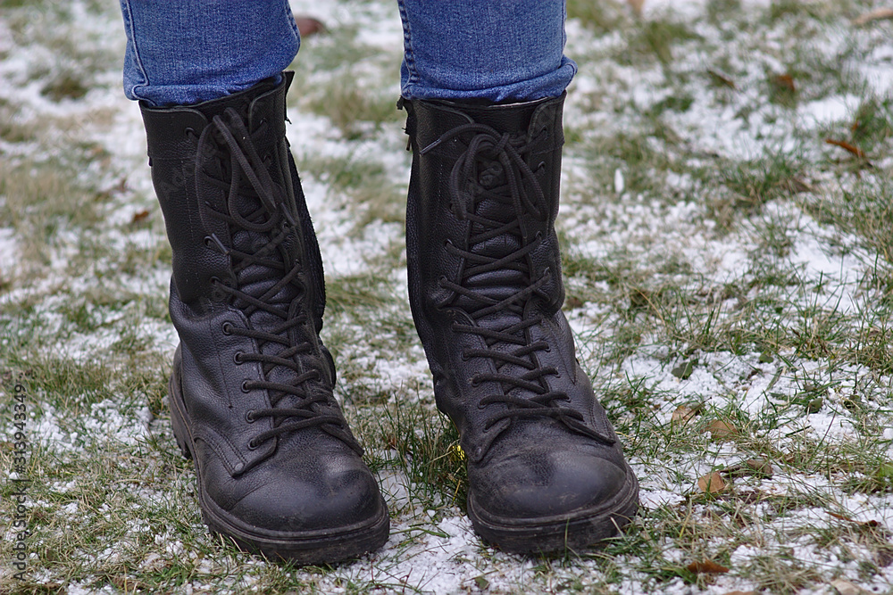 feet in high boots on the snow-dusted grass