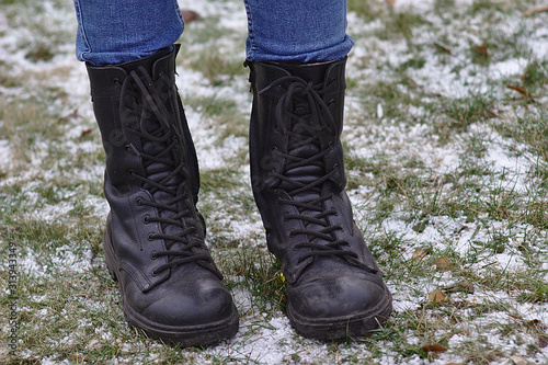 feet in high boots on the snow-dusted grass