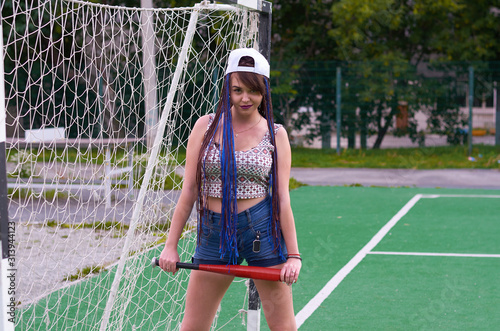 girl with dreadlocks in shorts with a baseball bat on a football field © евгений ставников