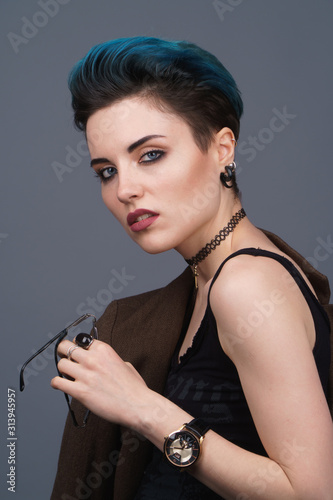 Studio photoshoot of a beautiful girl with blue hair and a fashion make-up in a brown jacket. Fashion style