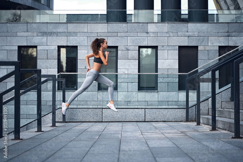 Young athletic woman running upstairs, jumping training at urban city stadium
