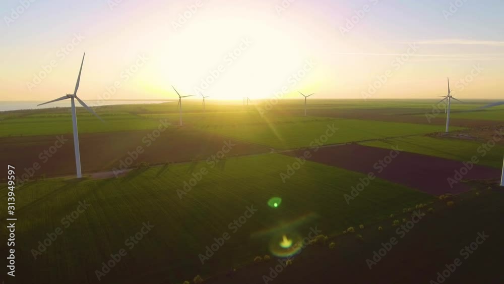 Wind turbine farm on beautiful evening landscape. Renewable energy production for green ecological world. Aerial view of wind mills farm park on evening Wind turbine farm on beautiful evening landscape. Renewable energy production for green ecological world. Aerial view of wind mills farm park on evening