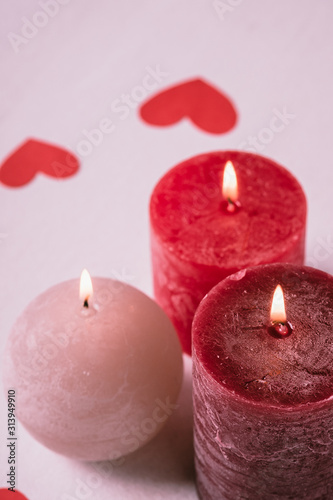 Three wax flame candlelight with paper red hearts valentines on white background, love dating, Valentine's day, selective focus
