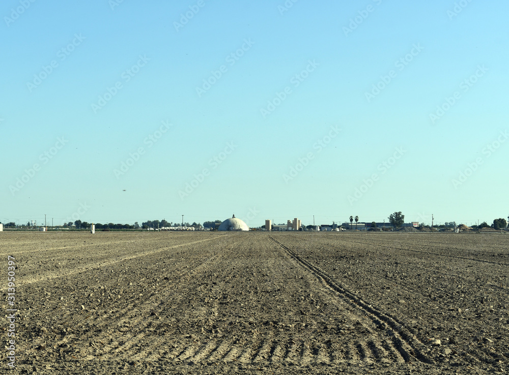 Freshly plowed field in front of factory Freshly plowed field in front of factory
