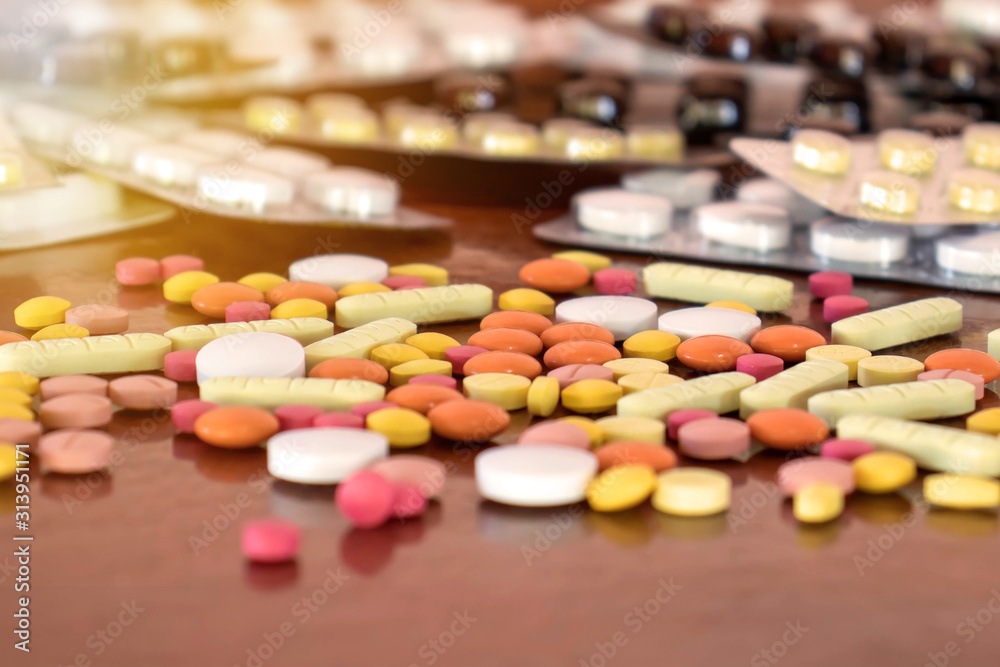 Many tablets of various colors on a wooden floor. The concept of drug use. Many tablets of various colors on a wooden floor. The concept of drug use.