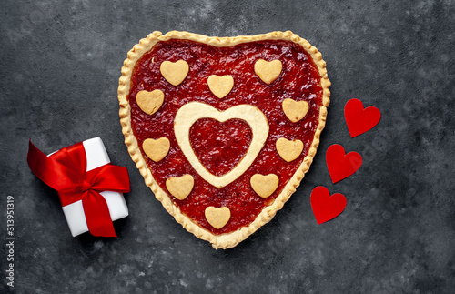 heart-shaped cake with jam and a gift with a red ribbon, on a stone background with copy space for your text. valentine's day celebration concept
