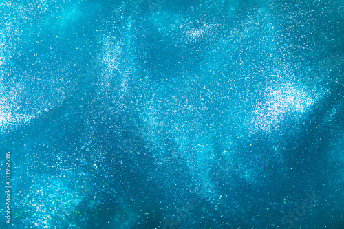 Abstract elegant, detailed blue glitter particles flow with shallow depth of field underwater. Holiday magic shimmering underwater space luxury background. Festive sparkles and lights