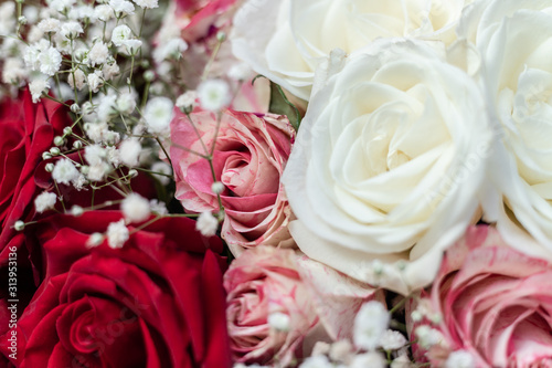 A bouquet of white  red and pink spotted roses  decorated with Gypsophila.