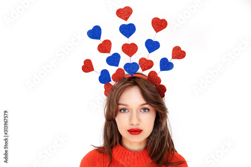 Beautiful Girl female with red plump lips, red sweater and crown of shiny glitter hearts isolated on white backdrop. Concept for valentine’s day. Festive greeting card with copy space. Selective focus