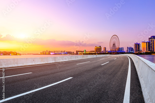 Empty asphalt highway and Suzhou city skyline with beautiful colorful sky at sunset.