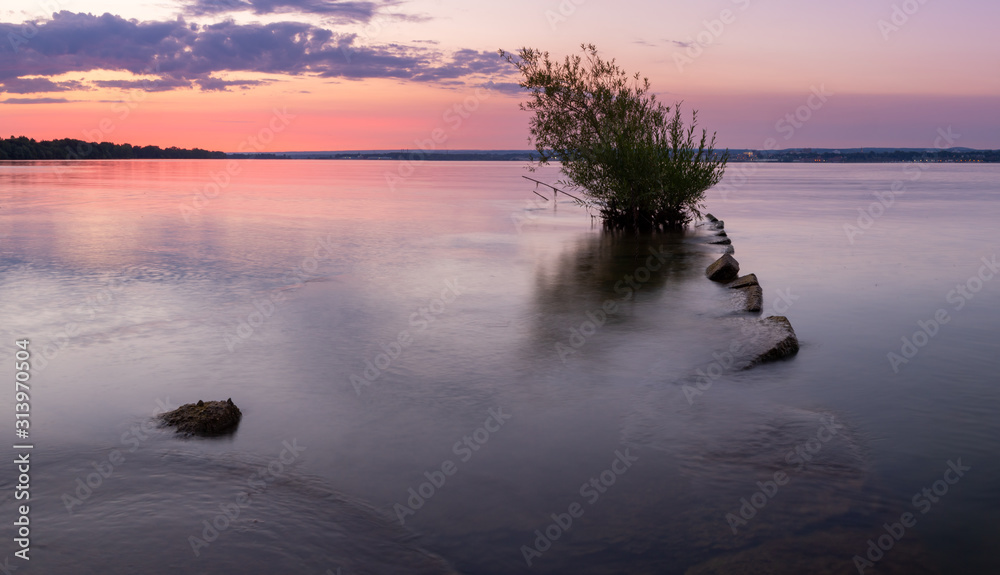 Fototapeta premium old fishing pier with tree at the end glass like water during colorful sky at sunrise or sunset. Presque Isle Bay in Erie, Pennsylvania
