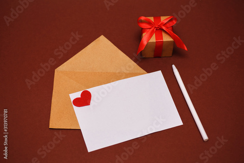 View from above. Handmade greeting card with a red heart. February 14th is a celebration of love. Valentine day concept with copy space, gift box tied with a red ribbon