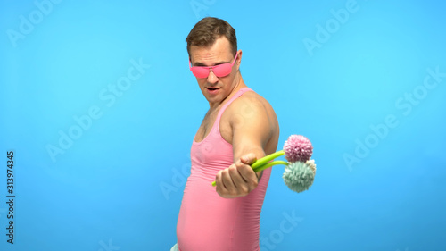 handsome man freak in pink glasses with a bouquet of flowers. blue background photo