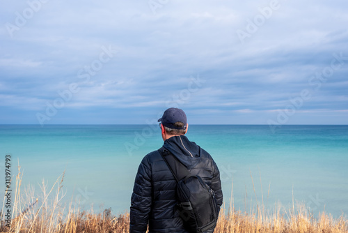 Man enjoying the scenic turquoise water of Lake Michigan in winter © Kristen