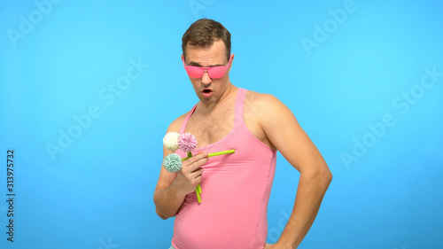 handsome man freak in pink glasses with a bouquet of flowers. blue background photo