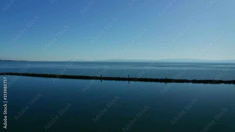 The breaker keeps the high waters from crashing into the shore on a sunny blue sky day.