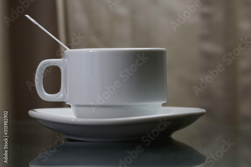 A white coffee cup with  plastic spoon over black background.