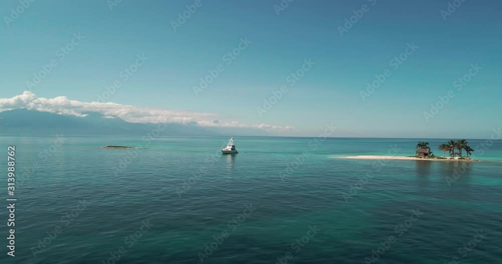 Low aerial tracking shot of luxury yacht in calm tropical reef waters, Honduras Low aerial tracking shot of luxury yacht in calm tropical reef waters, Honduras