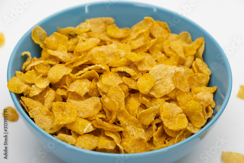 Golden cornflakes in the blue bowl isolated on white background