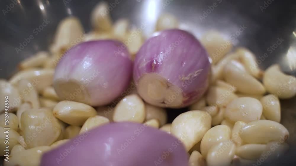 A lot of garlic being covered with shallots. These ingredients are then put in a food processor to be minced. A lot of garlic being covered with shallots. These ingredients are then put in a food processor to be minced.