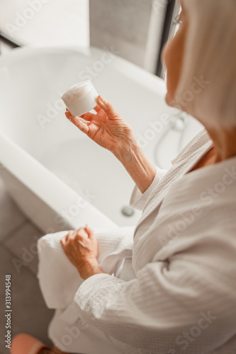 Wallpaper Mural Elderly woman in bathrobe holding jar of cream Torontodigital.ca