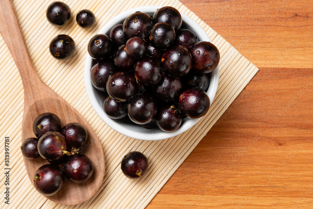 Jabuticaba in the bowl and wooden spoon - top view. Jaboticaba or Jabuticaba is the native Brazilian grape tree. Species Plinia Cauliflora. Brazilian Berry. Jabuticaba in the bowl and wooden spoon - top view. Jaboticaba or Jabuticaba is the native Brazilian grape tree. Species Plinia Cauliflora. Brazilian Berry.