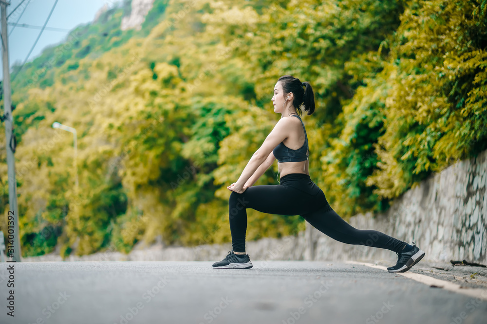 Asian fitness woman runner stretching legs before run outdoor workout in the park. Healthy Concept