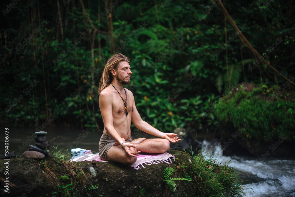 Yoga practice and meditation in nature. Man practicing near river Yoga practice and meditation in nature. Man practicing near river