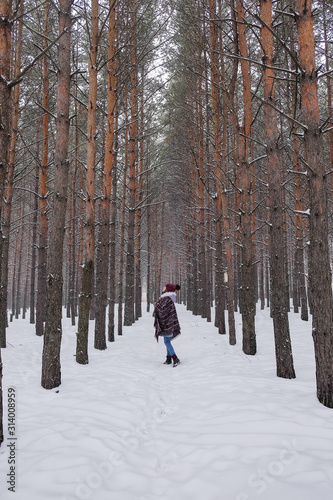 Portrait of a girl in a warm gray coat and burgundy knit scarf in the winter woods. © evelinphoto