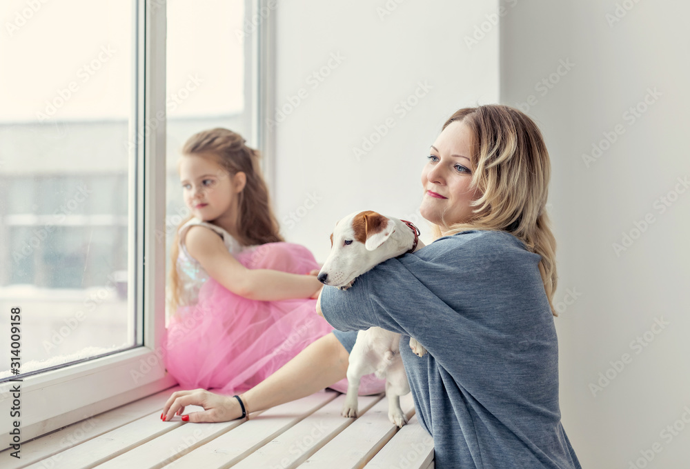Family and pet concept - mother and daughter playing with jack russell terrier dog at home