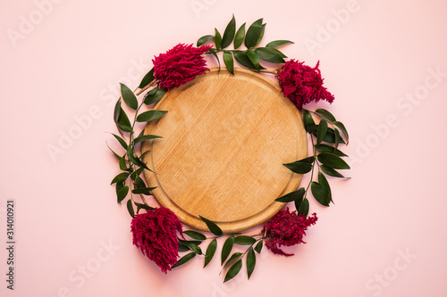 Arch of fresh flowers lie on a pink background - Wooden cutting board in the center. Copy space
