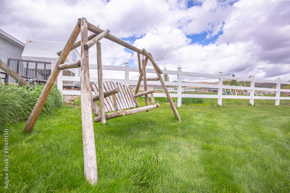 Old wooden garden swing on lush green grasses inside white picket fence Old wooden garden swing on lush green grasses inside white picket fence
