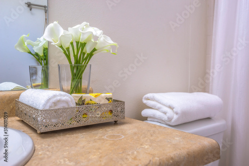 Valokuva Towels flowers and tissue on teh countertop beside the toilet of a bathroom