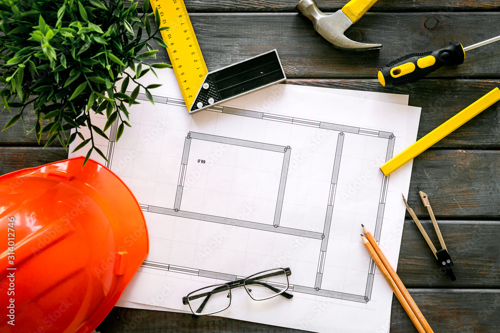 Construction concept. Helmet, instruments, blueprints on dark wooden background top-down