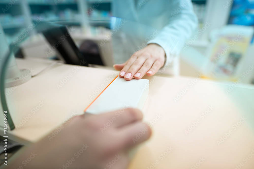Pharmacist selling medicine to the customer at drug store. Close up view of hands giving medicine box to patient. Medicine purchase. Pharmacist selling medicine to the customer at drug store. Close up view of hands giving medicine box to patient. Medicine purchase.
