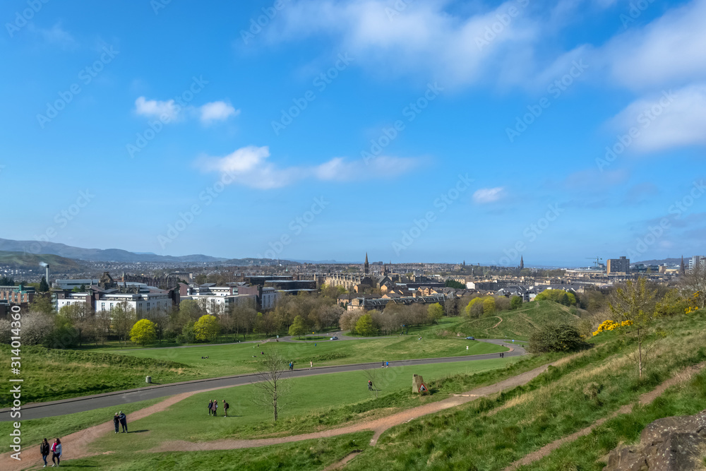General aerial view from the Holyrood Park to the Edinburgh downtown city, monument buildings, mountains and parks on background