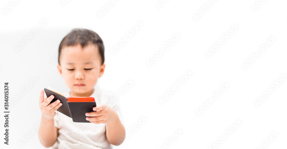 Cute little asian toddler boy in white t-shirt reading bible before sleep.Hands holding on a Holy Bible in bed room concept for faith, spirituality and religion.isolated on white background.