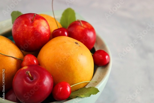 Bowl of mixed or assorted fruits and berries on the table  Raw mangoes  Mangoes  Red cherries and Fresh Plums. Moody photography  dark background