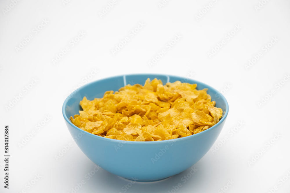 Golden cornflakes in the blue bowl isolated on white background Golden cornflakes in the blue bowl isolated on white background